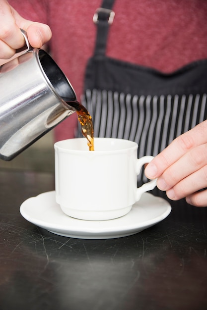 Close-up of man pouring coffee in the white cup