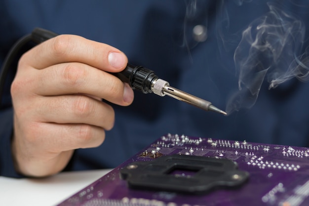 Close-up man repairing a computer motherboard