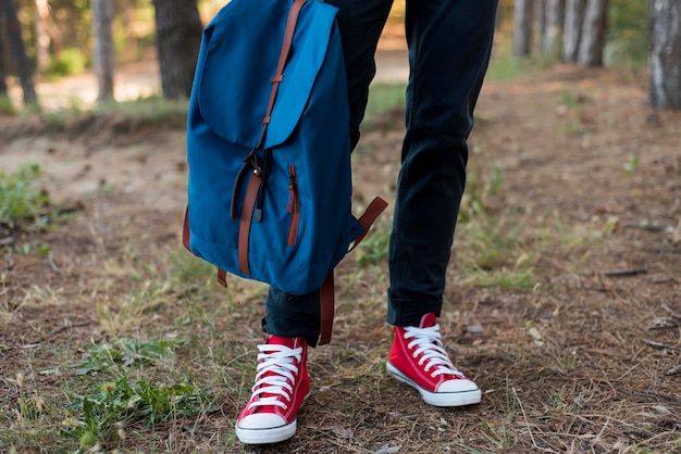 Close-up man's feet and backpack in forest