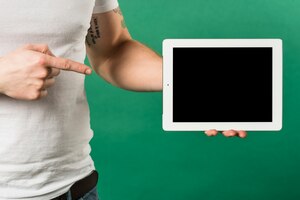 Close-up of man's finger pointing the finger toward digital tablet with black screen display