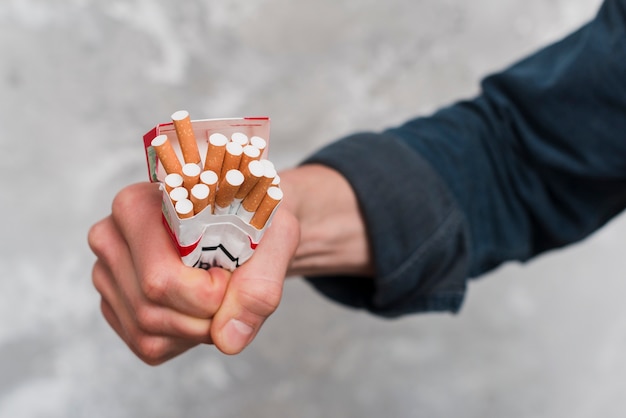 Free photo close-up of man's hand crushing cigarettes box