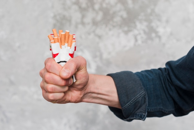 담배 패킷을 분쇄하는 사람의 손 클로즈업