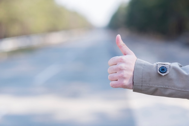 Foto gratuita primo piano della mano dell'uomo autostop alla strada della campagna