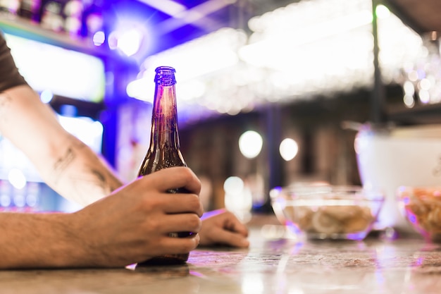 Close-up of man's hand holding beer bottle in the bar