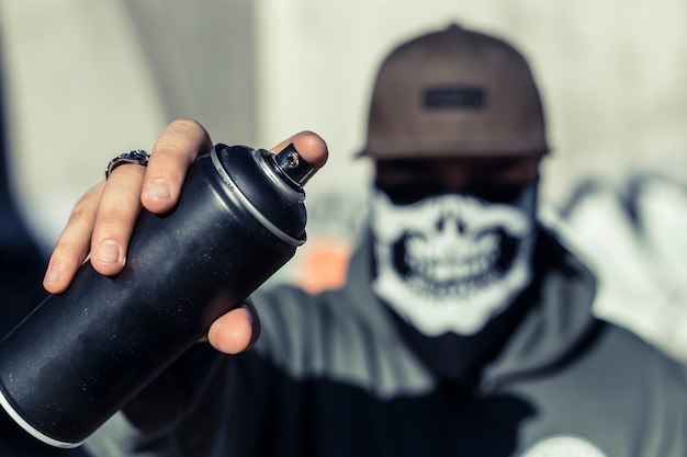 Close-up of a man's hand holding black aerosol can