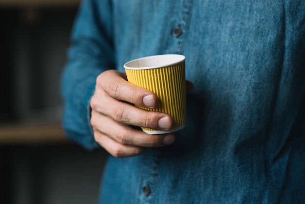 Close-up of a man's hand holding disposable coffee cup