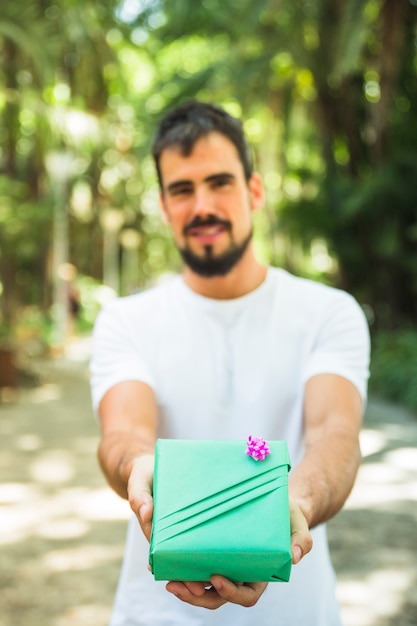 Primo piano della mano di un uomo che tiene il contenitore di regalo verde