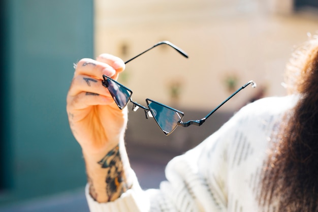 Foto gratuita primo piano della mano dell'uomo che tiene in mano gli occhiali da sole durante l'estate