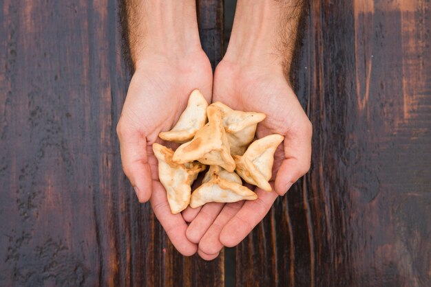 Close-up of a man's hand showing dumplings against wooden texture backdrop