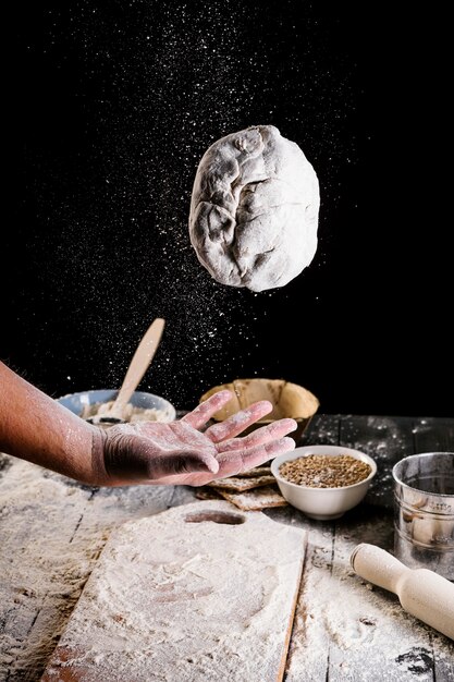 Крупный план руки человека, бросая хлебное тесто в воздух