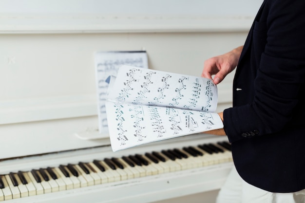 Крупный план мужской руки перелистывая страницу музыкального листа
