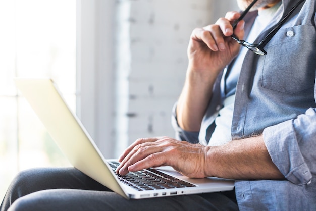 Close-up of man's hand typing on laptop