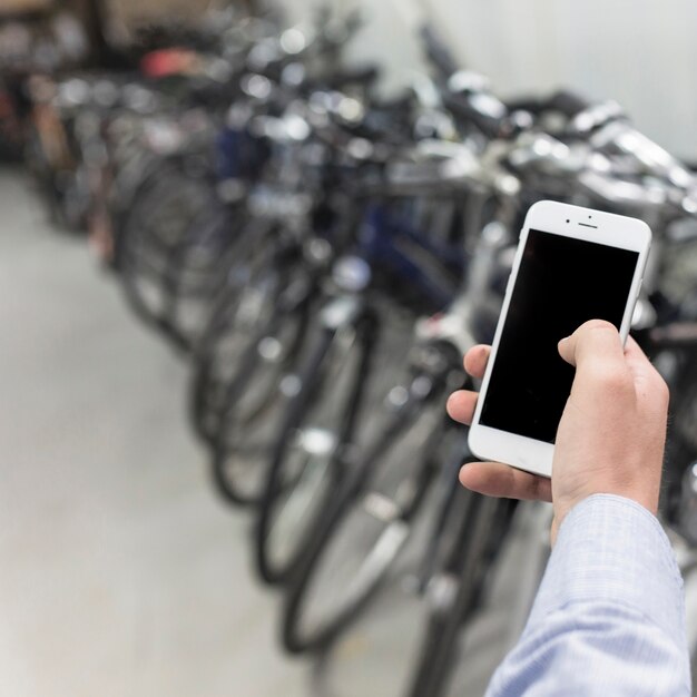자전거 워크숍에서 핸드폰을 사용하여 사람의 손 클로즈업