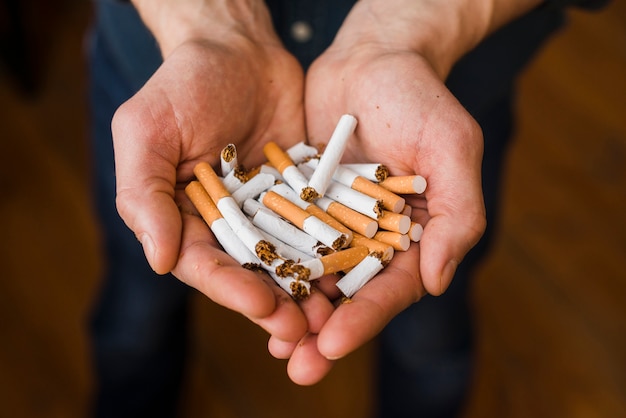 Free photo close-up of man's hand with bunch of breaking cigarette