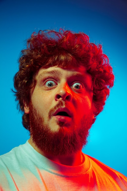 Close up man's portrait isolated on blue studio wall in red neon light