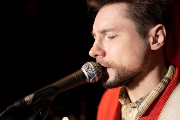 Free photo close up man singing with microphone