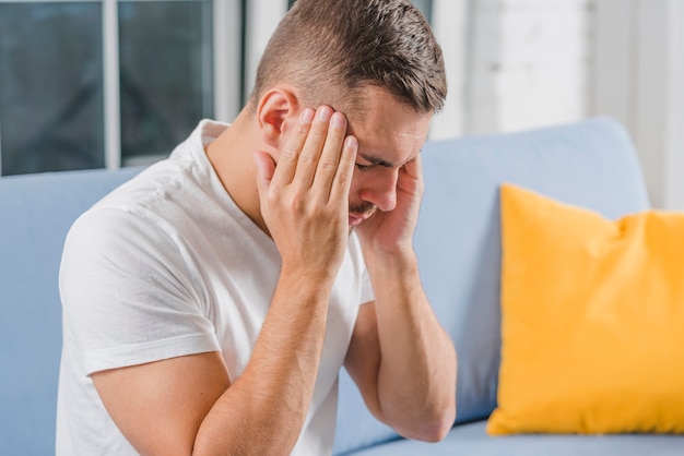 Free photo close-up of a man sitting on sofa suffering from headache