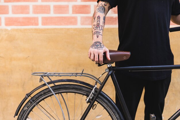 Close-up of a man standing with bicycle in front of wall