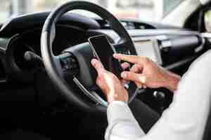 Free photo close-up man at steer wheel checking phone