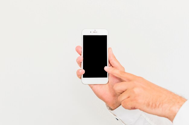 close-up of a man touching smartphone screen against white background