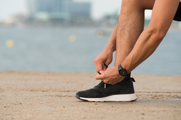 Free photo close-up of man tying shoelaces outdoors