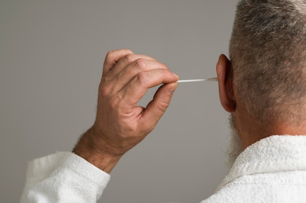 Free photo close up man using cotton swab