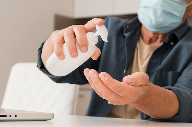 Foto gratuita uomo del primo piano che usando disinfettante