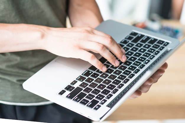 Close-up of man using laptop keypad