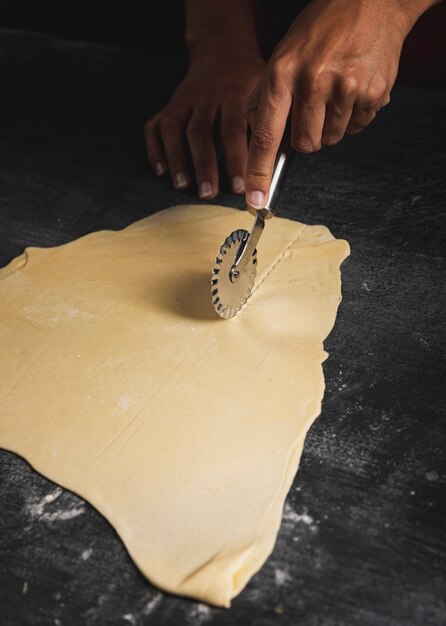 Close-up man using pizza cutter 