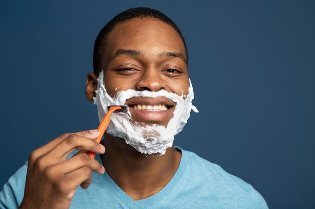 Close up man using razor to shave