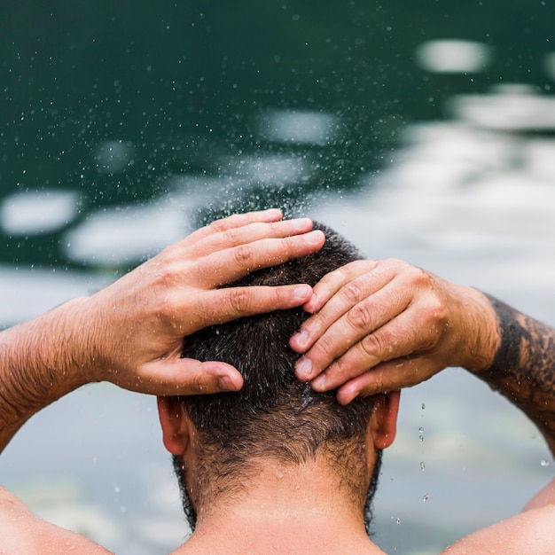 Foto gratuita primo piano di uomo che si lava la testa con acqua di lago