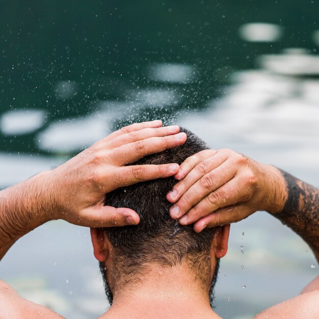 彼の頭を湖の水で洗う男のクローズアップ