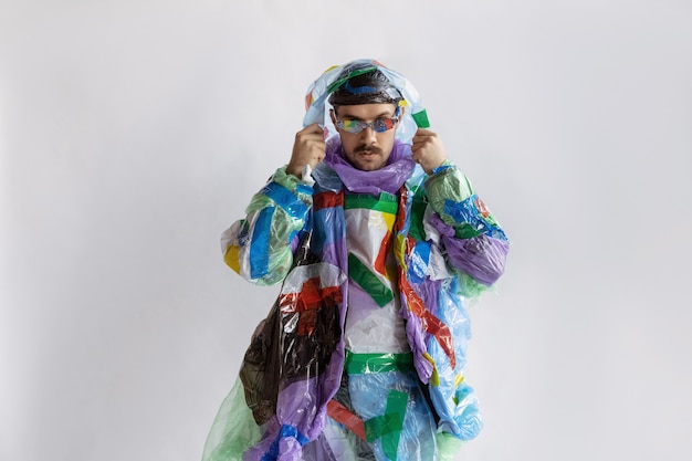 Close up of man wearing plastic on white wall. Male model in clothes made of garbage. Fashion, style, recycling, eco and environmental concept. Too much pollution, we're eating and taking it.