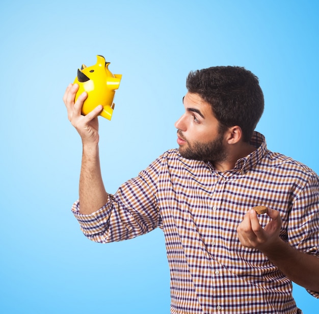 Close-up of man, who looking in piggy bank