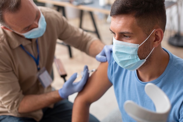 Free photo close up man with mask getting vaccinated