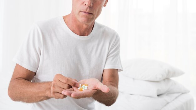 Close-up man with pills in the bedroom