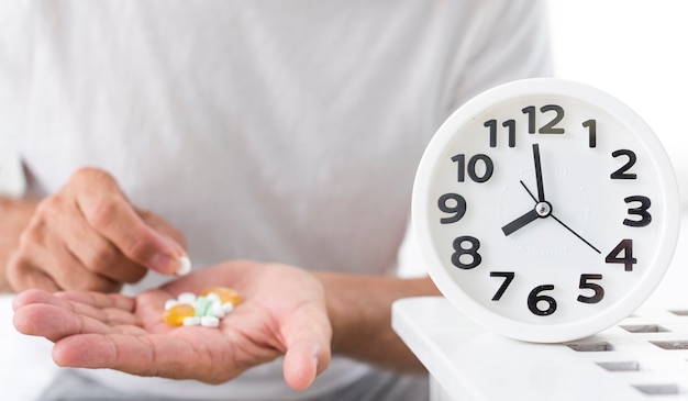 Close-up man with pills and clock