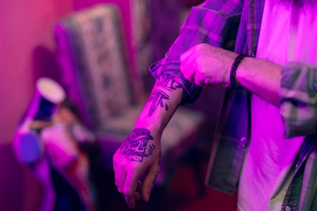 Free photo close-up of a man with tattoo on his hand folding the shirt sleeves