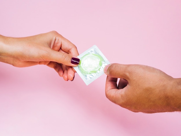 Close-up man and woman holding a green condom