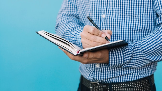 Close up of man writing in book