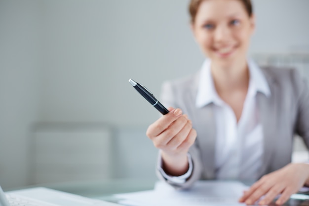 Close-up of manager holding a pen with blurred background