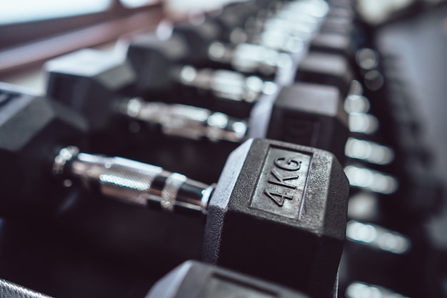 Close up of many metal dumbbells on rack in sport fitness center.