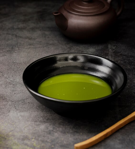 Close-up of matcha tea in bowl with teapot