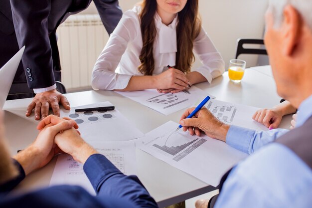 Close-up of mature businessman analyzing the graph with his colleagues