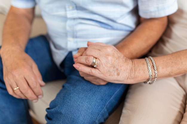 Free photo close up of mature old husband and wife hold hands show love and care senior couple holding hands while sitting together at home elderly relationships marriage concept