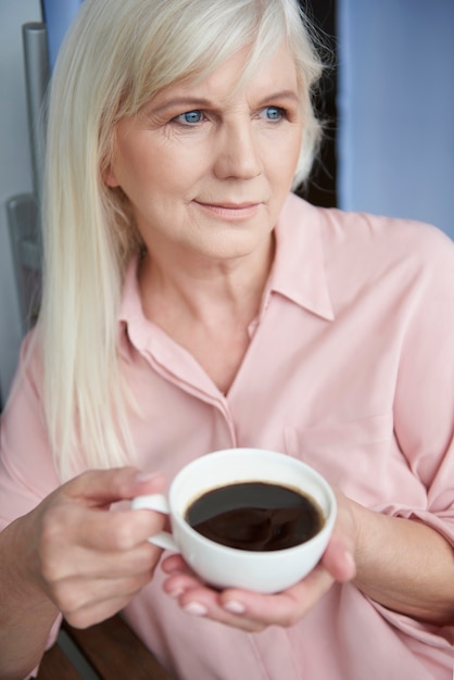 バルコニーでおいしいコーヒーを楽しんでいる成熟した女性にクローズアップ