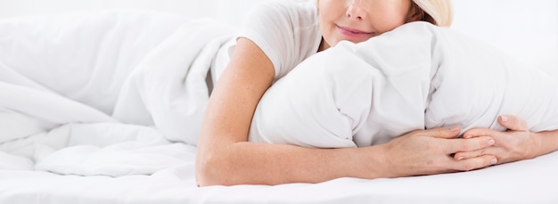 Крупным планом зрелая женщина, держащая подушку
