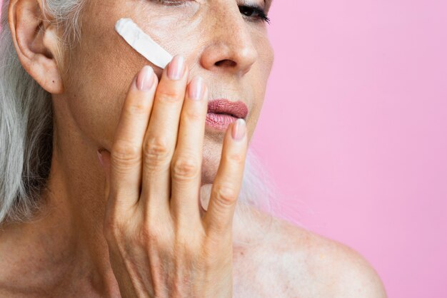 Close-up mature woman with moisturizer