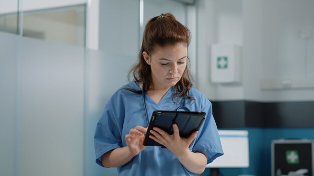 Close up of medical assistant looking at tablet screen with information