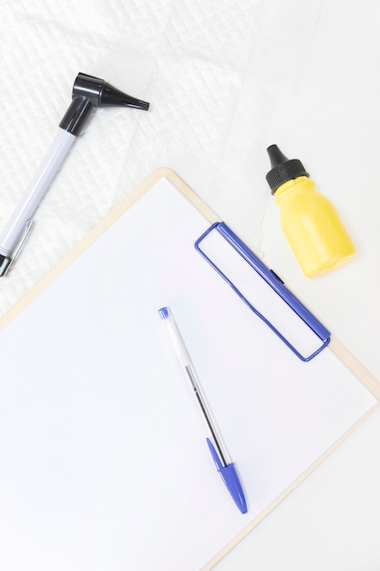 Free photo close-up of medicine bottle; otoscope and pen with clipboard